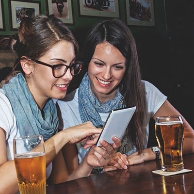 Young women with a tablet at the bar with glasses of beer Young women with a tablet at the bar with glasses of beer